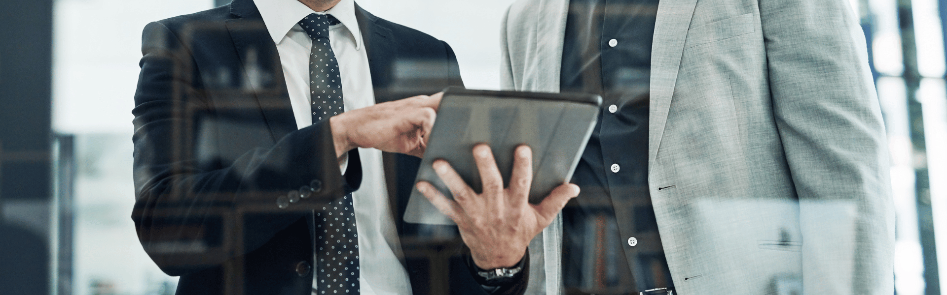 Two males in suits looking at an electronic device