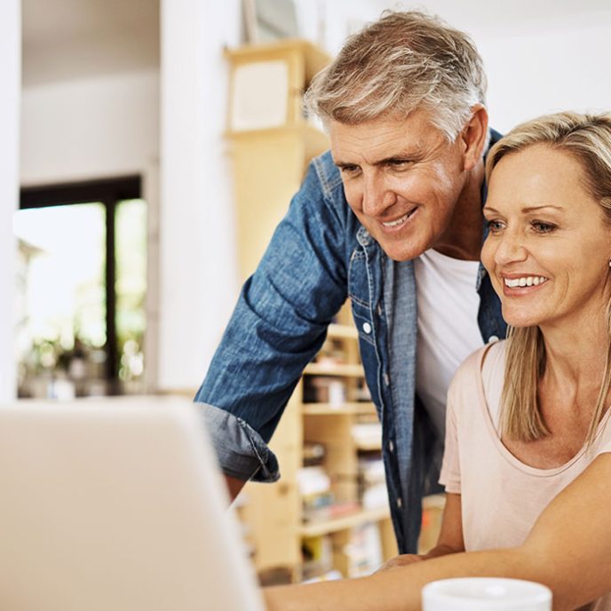 Mature couple, smile and laptop research at home with happiness and computer. NHS Pension Scheme Introduction Webinar