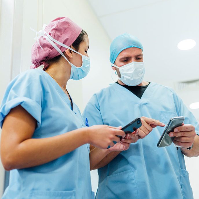 Doctors using cell phones in the hospital corridor checking payslips