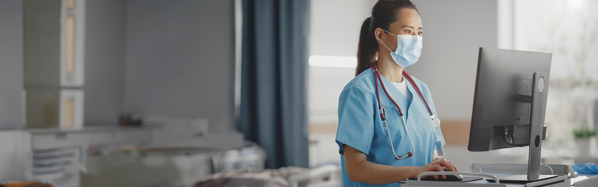 digital and it framework agreement. NHS nurse working on a computer inside a hospital ward.