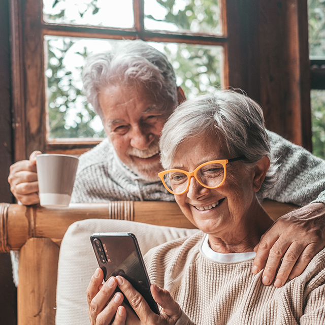 NHS Pension Services by NHS SBS. An older couple drinking tea checking looking at a mobile phone