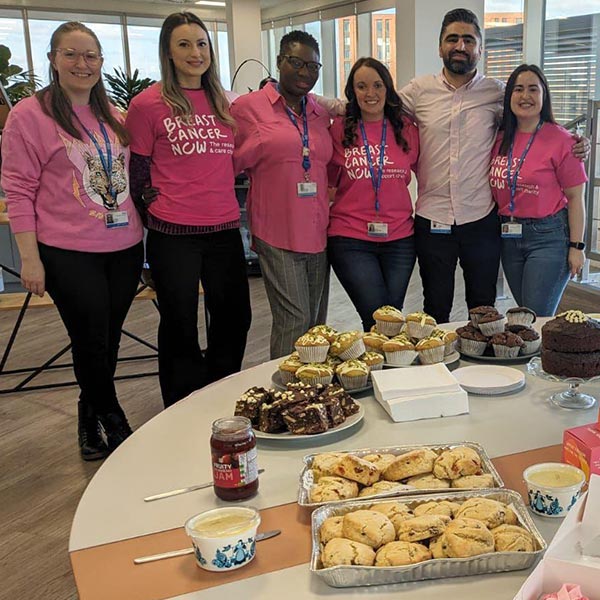 NHS SBS colleagues pose in front of their homemade cakes for a fundraising event for The Breast Cancer now, the research and support charity.