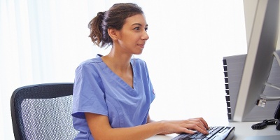 Female Doctor In Office Working At Computer