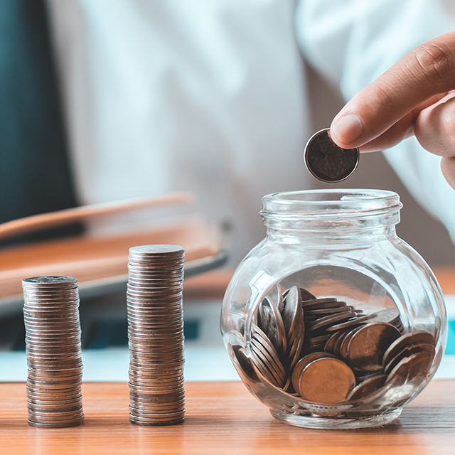 vat-consultancy services for the NHS. Counting money into a glass jar